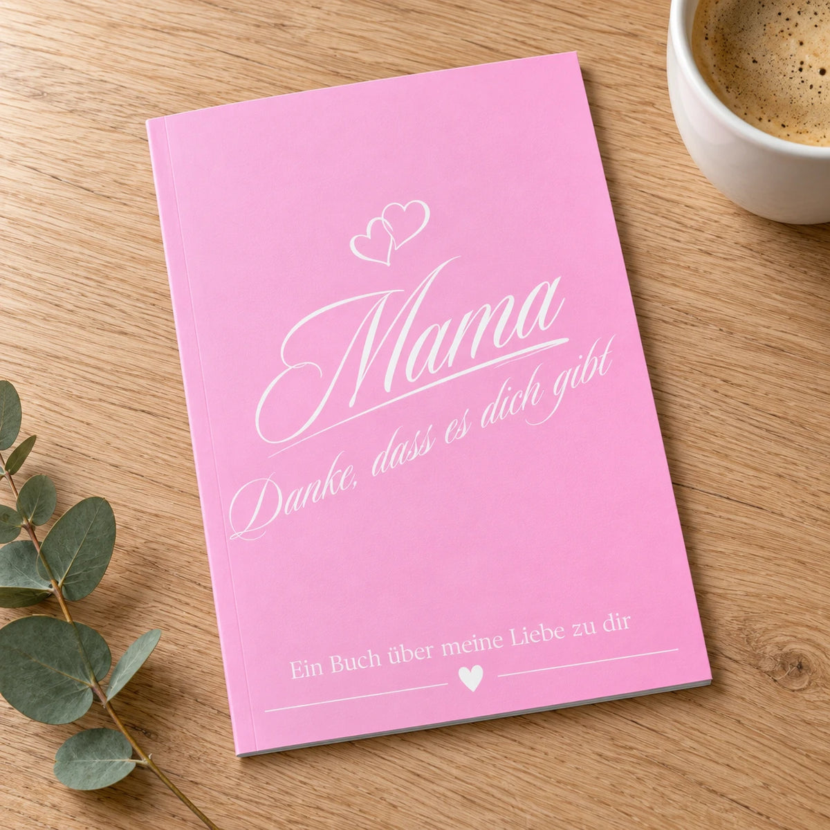 Buch Mama – Danke, dass es dich gibt, rosa Einband, auf einem Eichentisch neben einer Tasse Kaffee