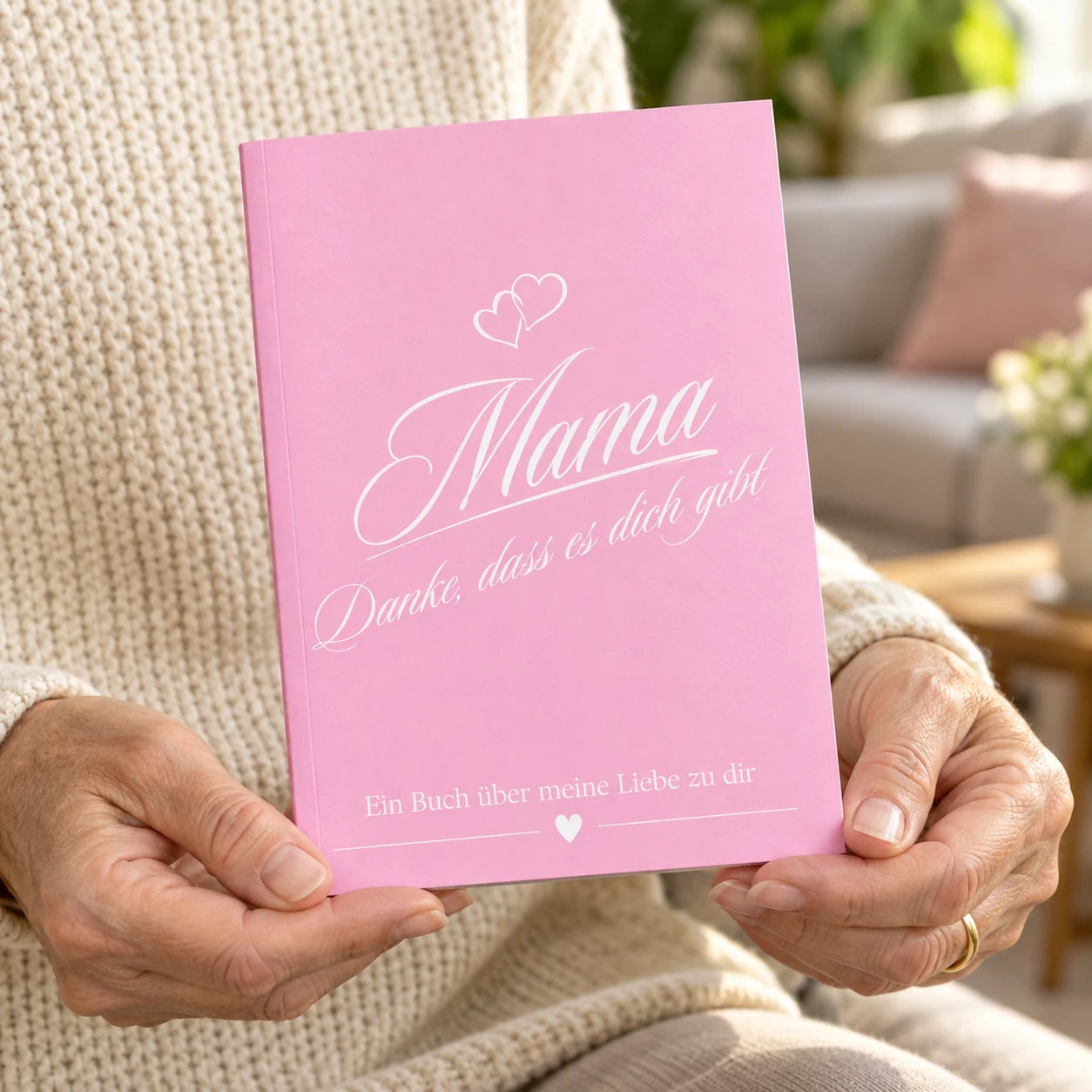 Frau hält das rosa Buch Mama – Danke, dass es dich gibt in den Händen