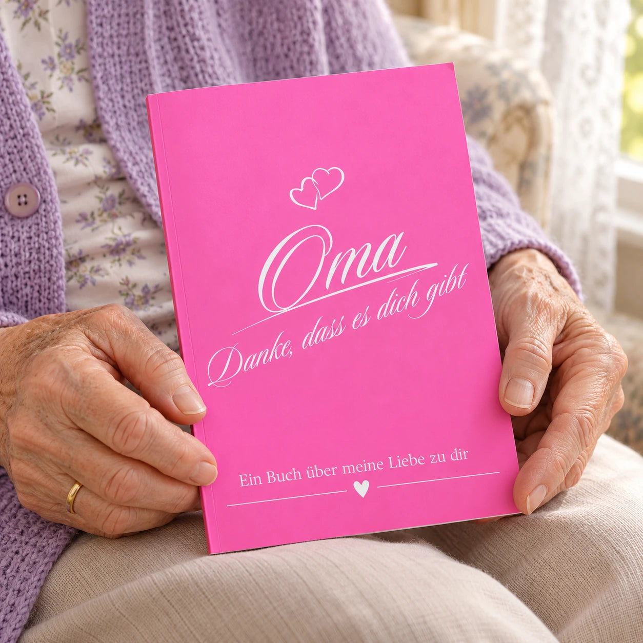 Ältere Frau hält das pinke Buch Oma – Danke, dass es dich gibt in den Händen