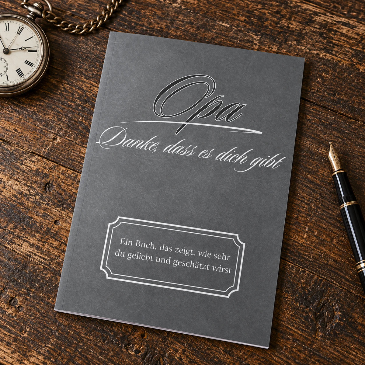 Buch Opa – Danke, dass es dich gibt, anthrazitfarbener Einband, auf einem Schreibtisch neben Taschenuhr und Füller