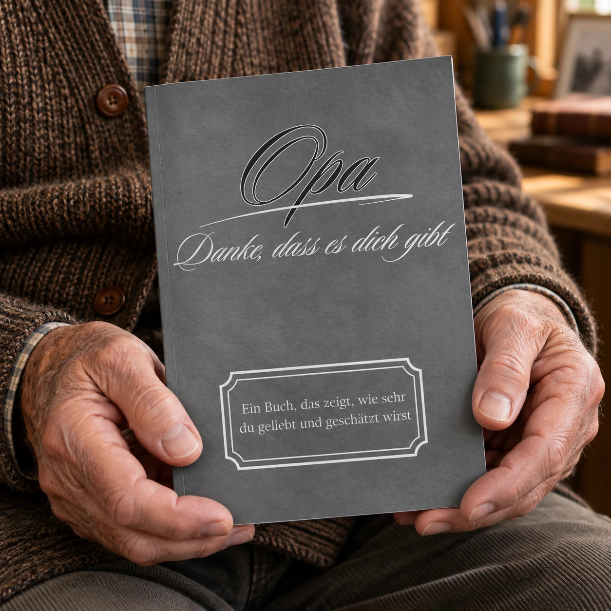 Älterer Mann hält das anthrazitfarbene Buch Opa – Danke, dass es dich gibt in den Händen