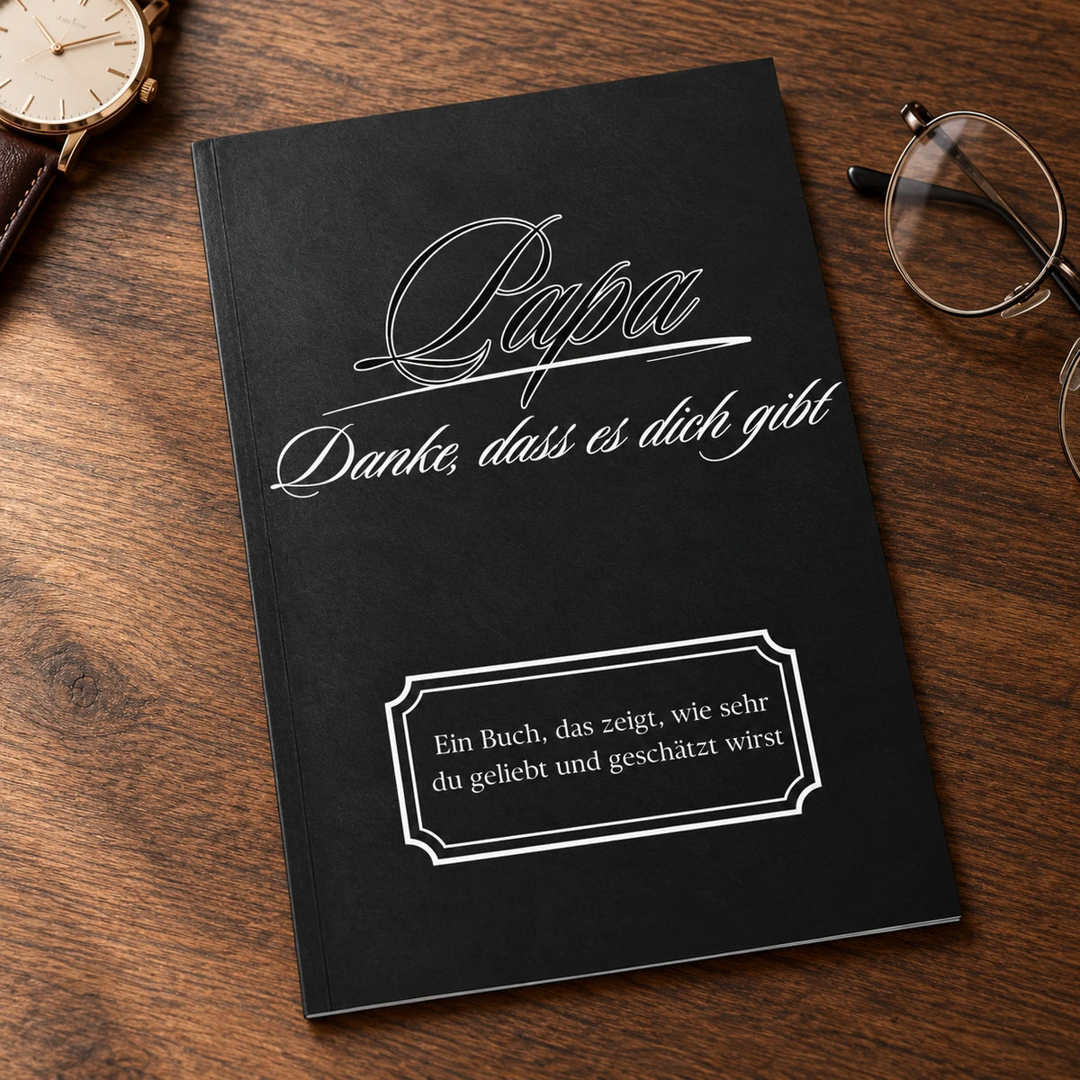 Buch Papa – Danke, dass es dich gibt, schwarzer Einband, auf einem Holztisch neben Uhr und Lesebrille