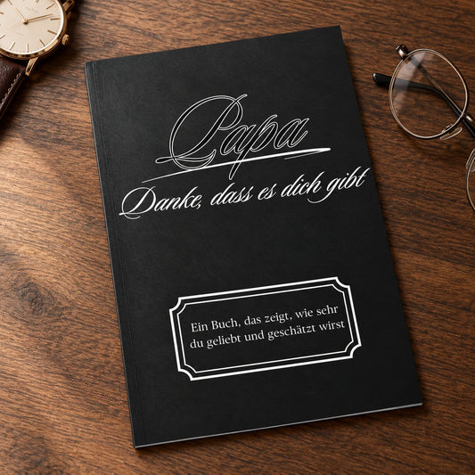 Buch Papa – Danke, dass es dich gibt, schwarzer Einband, auf einem Holztisch neben Uhr und Lesebrille